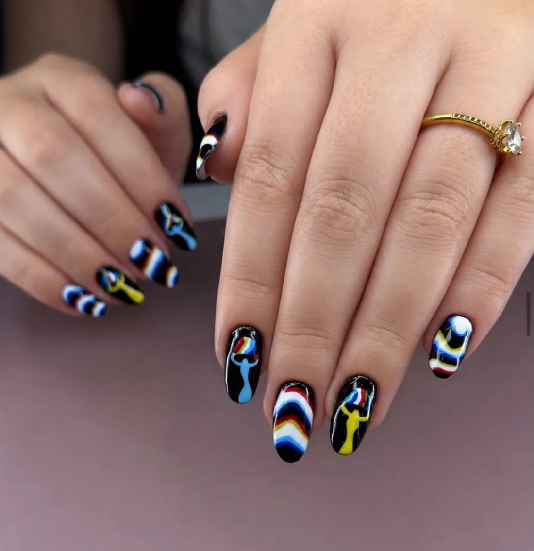 Nail art colorida com grafismos sobre fundo preto